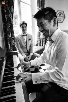   At Chateau de Santeny in Val de Marne, Ile de France, the groom and his best man share quiet smiles at the piano moments before the ceremony, reflecting their close friendship.